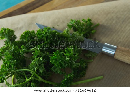 Close-up of coriander leaves, wax paper and knife on chopping board