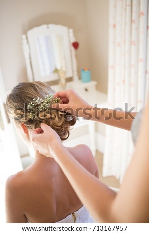 Cropped hands of bridesmaid adjusting bride hair in dressing room