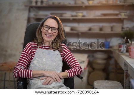 Female potter relaxing on chair in pottery shop