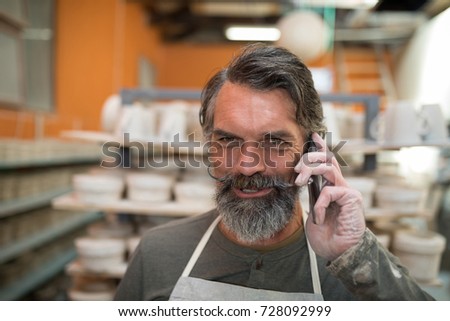 Male potter talking on mobile phone in pottery shop