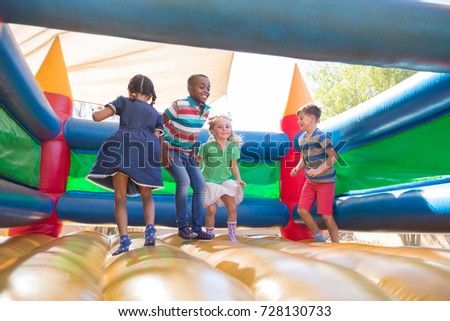 Full length of friends playing on bouncy castle at playground