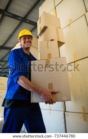 Portrait of worker holding a cardboard boxes while walking in olive factory