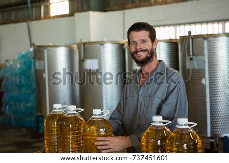 Portrait of smiling worker holding a can of olive oil in factory