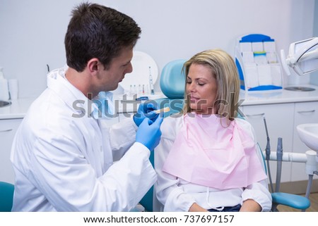 Side view of young doctor showing dental mold to patient at dental clinic
