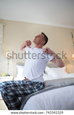Man waking up in bed and stretching his arms at home