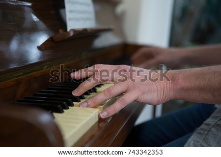 Close-up of man playing piano at home