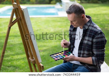 Man painting on canvas in garden on a sunny day