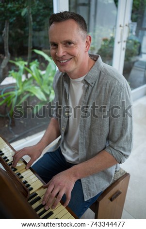 Portrait of smiling man playing piano at home