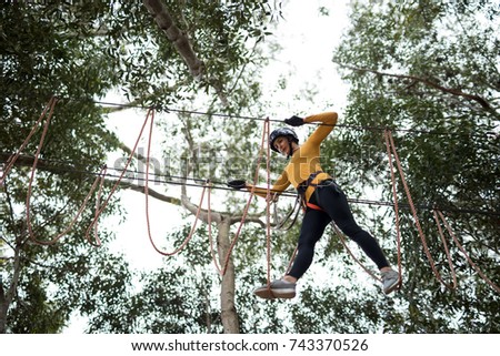 Woman enjoying zip line adventure in park on a sunny day