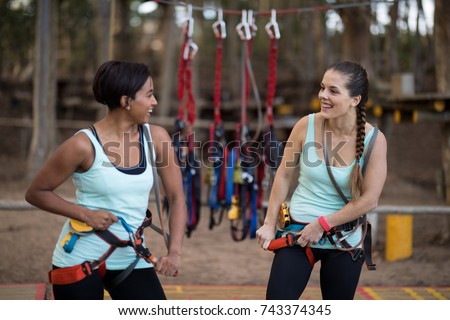 Happy female friends getting their belt tied to perform zip line
