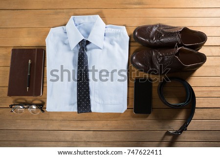 Overhead view of folded shirt and accessories arranged on wooden plank