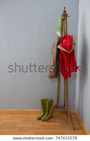 Umbrella, warm clothing and wellington boots arranged on wooden stand