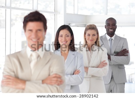 Young Business man with arms folded in front of Business Team (Focus on man in back)
