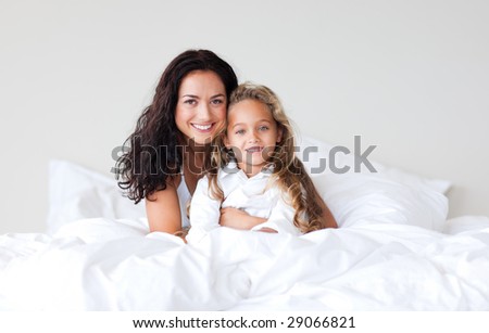Young Mother and her daughter on bed smiling at camera