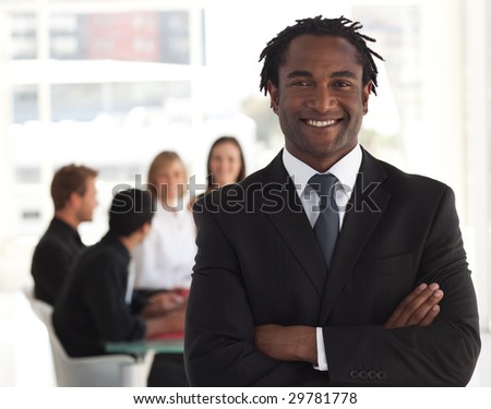 Senior business leader standing and smiling in front of his team