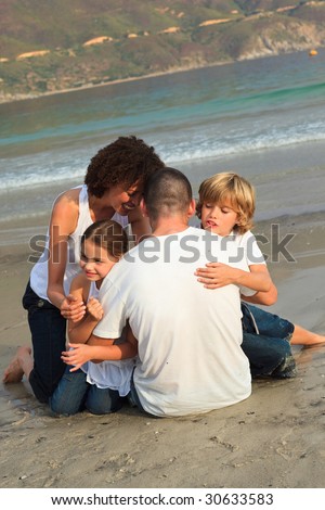 Young Family hugging on the beach