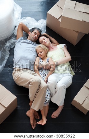 Famiy lying on floor with a lot of boxes after buying house