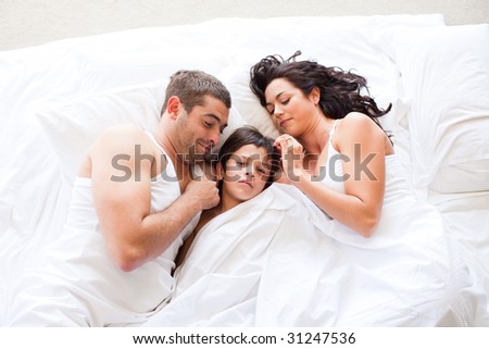 Nice family sleeping together in a white bed