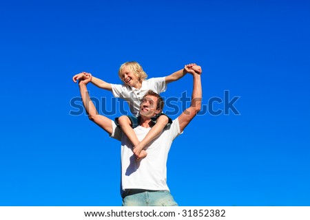 Smiling youth sitting on his father\'s shoulders