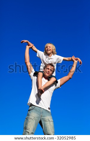Man giving young boy piggyback ride outdoors smiling