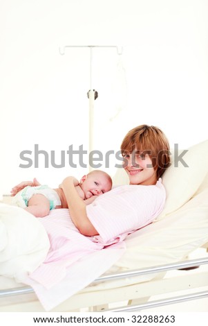 Patient with newborn baby in bed in hospital with copy-space