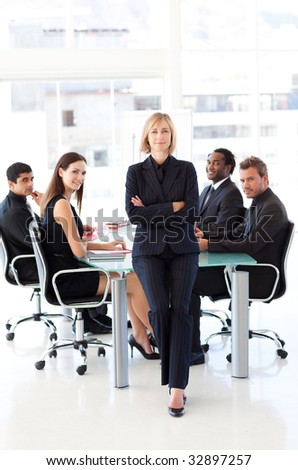Serious businesswoman looking at the camera with folded arms in a meeting