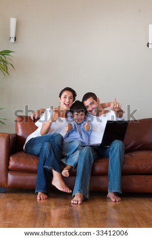 Parents and kid having fun with a laptop at home and copy-space