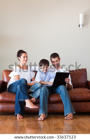 Parents and son playing with a laptop at home with copy-space