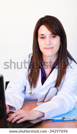 Brunette doctor working with a laptop and smiling at the camera