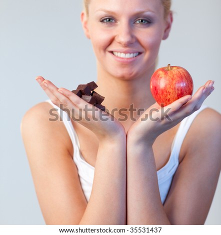 Beautiful woman showing  chocolate and apple and looking at the camera focus on chocolate and apple