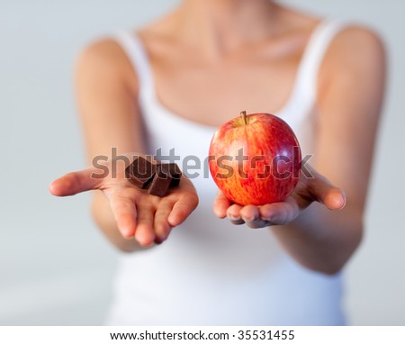Young beautiful woman showing chocolate and apple focus on chocolate