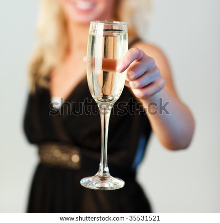 Beautiful woman holding a glass of champagne and smiling at the camera with focus on champagne