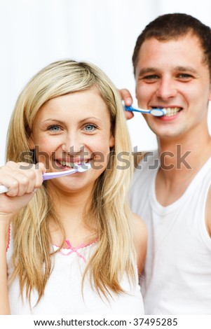 Couple cleaning their teeth in bathroom smiling at the camera