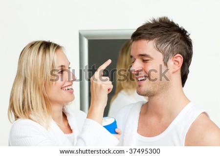 Wife putting cream on his husband\'s nose in bathroom