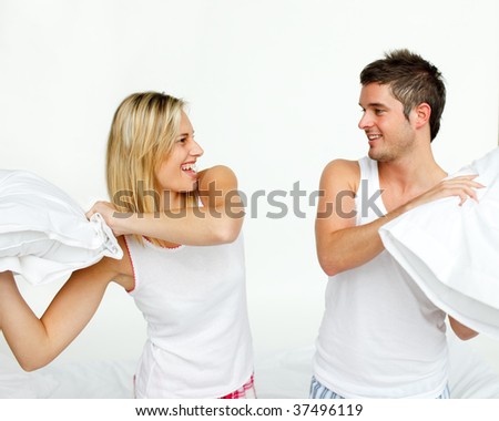 Young couple fighting with pillows in bed