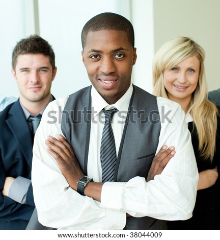Afro-American businessman with folded arms with his colleagues smiling at the camera