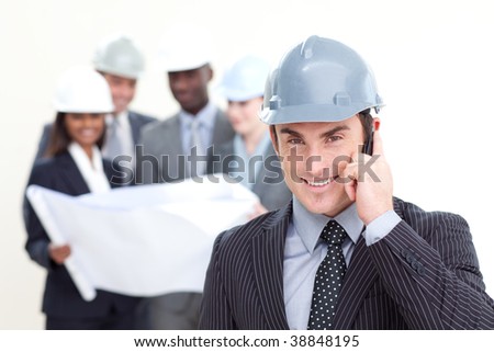 Confident male architect with his team in the background smiling at the camera