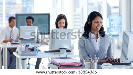 Ethnic businesswoman with a headset on in a call center with her colleagues
