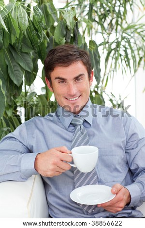 Happy businessman drinking a cup of coffee on sofa