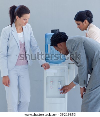 Business people drinking from a water cooler in office
