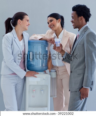 Business people speaking next to a water cooler in office
