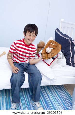 Smiling little boy playing baseball in his bedroom
