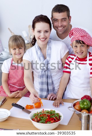 Happy young family cutting vegetables in kitchen