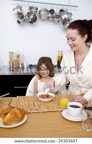 Daughter and mother in kitchen eating breakfast