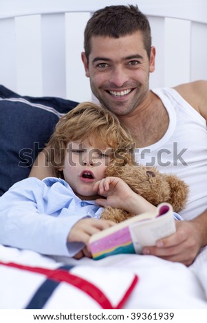 Father and son reading a book in bed together