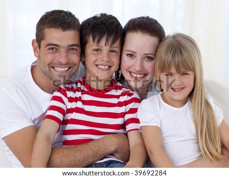 Portrait of smiling family in living-room sitting on sofa together