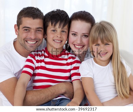 Portrait of happy family in living-room sitting on sofa together