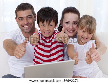 Happy family at home using a laptop with thumbs up