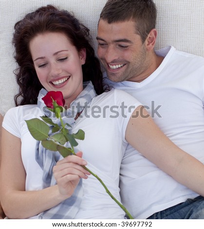 Lovely couple on sofa, woman holding a rose