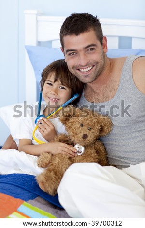 Father and  son playing doctors in bed with a teddy bear
